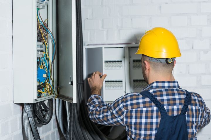 Electrician in a hard hat working on an electrical panel