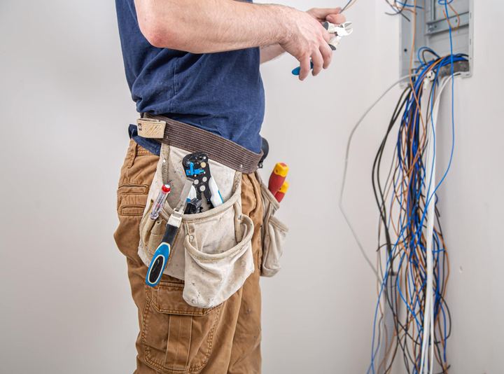 Electrician with a tool belt sorting wires