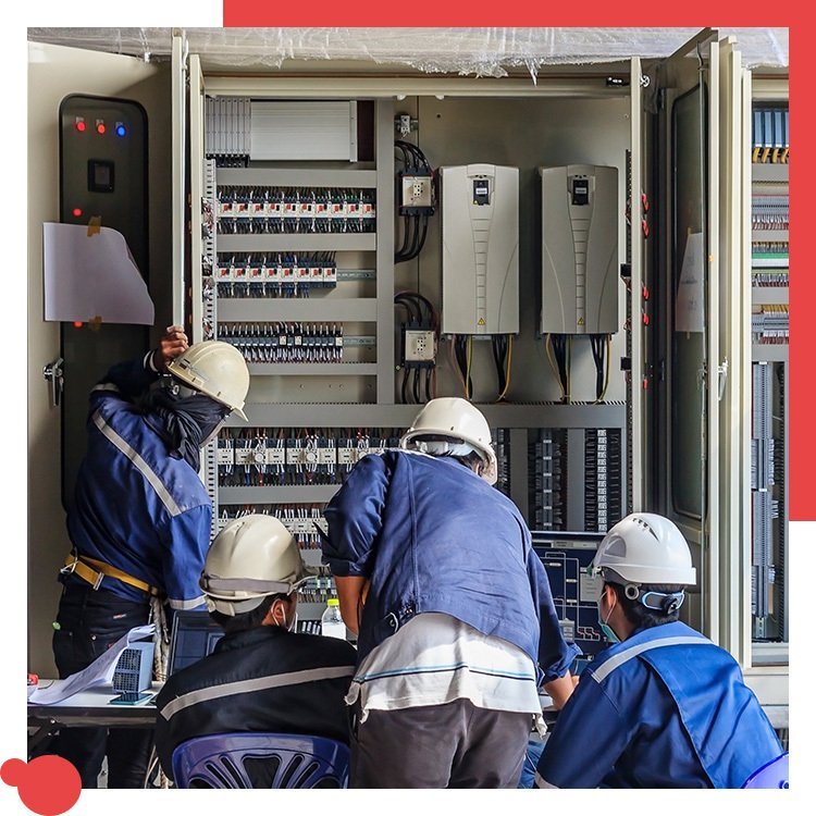 Electricians in hard hats working on a commercial electrical panel